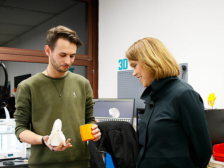Ein Student zeigt der Ministerin 3D-Objekte, die er mit einem 3D-Drucker in der Werkbox des CoLiLabs der PH Weingarten erstellt hat.