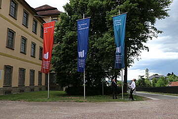 Drei Flaggen auf dem Kirchplatz im neuen Corporate Design 