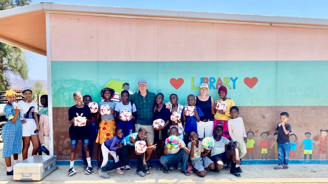Die Schülerinnen und Schüler freuen sich über neue Fußbälle. Gruppe mit Bällen